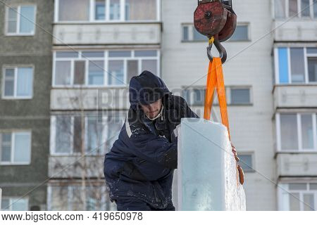 A Portrait Of A Fitter In A Blue Jacket At The Hook Of A Truck Crane