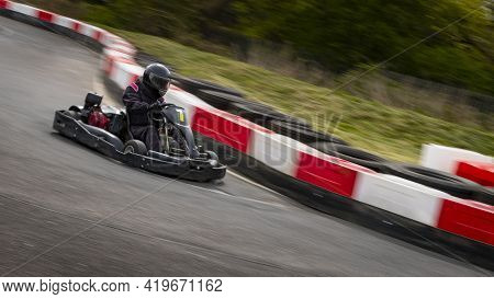 A Panning Shot Of A Racing Kart As It Circuits A Track.