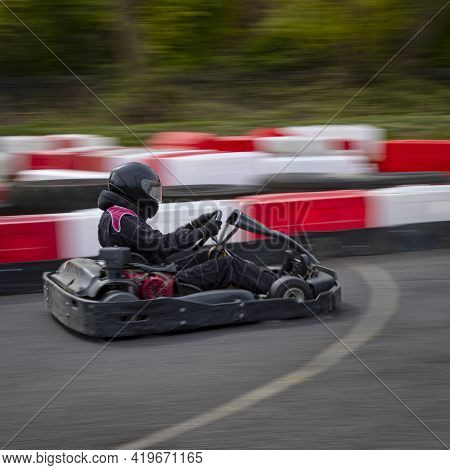 A Panning Shot Of A Racing Kart As It Circuits A Track.
