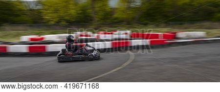 A Panning Shot Of A Racing Kart As It Circuits A Track.