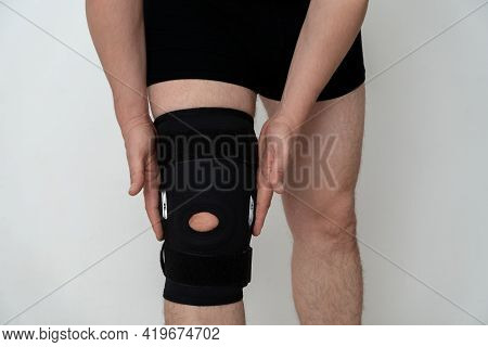 Leg Support. A Man Adjusts A Black Orthosis On His Leg. Copspace