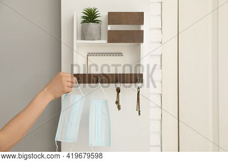 Woman Taking Protective Mask From Key Hanger In Hallway, Closeup