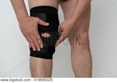 Leg Support. A Man Adjusts A Black Orthosis On His Leg. Copspace