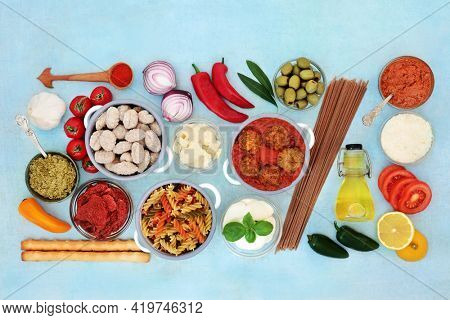 Healthy balanced Italian diet food high in antioxidants, anthocyanins, fibre, lycopene, omega 3 and protein. With meatballs, cheeses, vegetables, pasta, olive oil, sauces and herbs. On mottled blue.