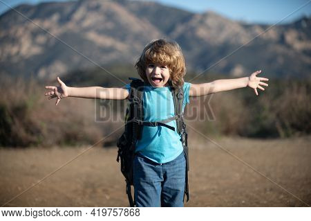 Child Boy With Backpack Hiking In Scenic Mountains. Kid Local Tourist Goes On A Local Hike.