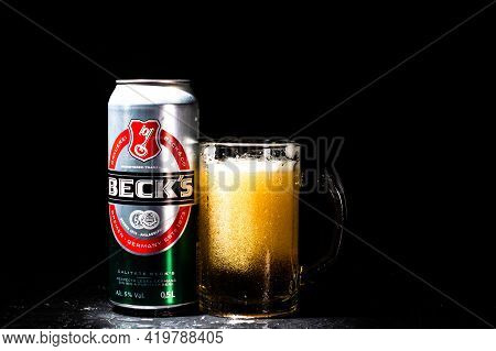 Can Of Beck`s Or Becks Beer And Beer Glass On Dark Background. Illustrative Editorial Photo Shot In