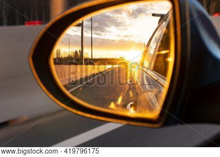 Rear View Car Mirror View Back To Nature On Evening With Sunset. Sunset Reflected In The Mirror Of T