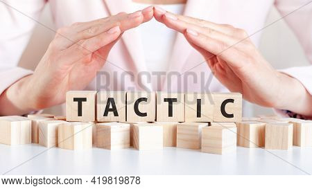 Businesswoman Holding Her Hands Over The Wooden Cubes With The Word Tactic, Concept
