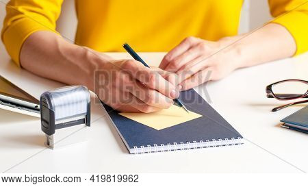 A Woman Writes Down Information With A Pen In A Diary