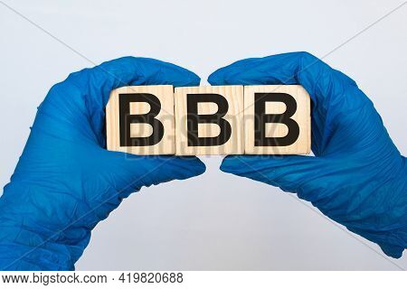 A Doctor Wearing Gloves Holds Wooden Cubes With The Inscription Bbb, Medical Concept