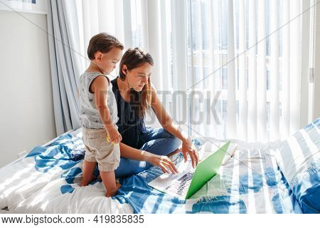 Work From Home With Kids. Busy Mother Working On Laptop With Baby Boy Toddler At Home. Remote Work, 