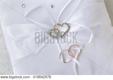 Empty White Pillow For Wedding Rings With Rhinestone Hearts On A Wooden Background. Soft Focus
