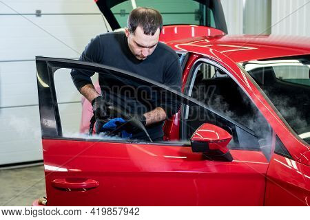 Car Service Worker Cleans Interiror With Steam Cleaner