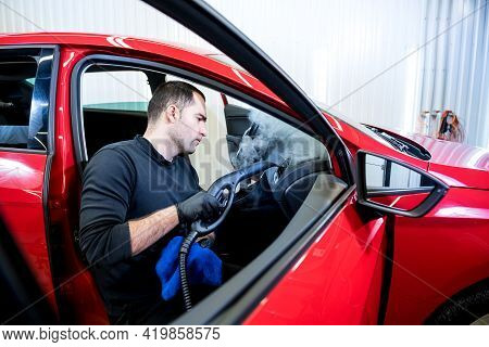 Car Service Worker Cleans Interiror With Steam Cleaner