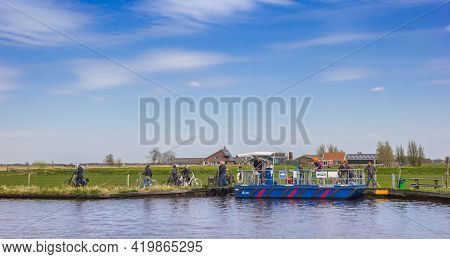 Grou, Netherlands - April 27, 2021: People Taking The Bicycle Ferry To Cross The River In Friesland 