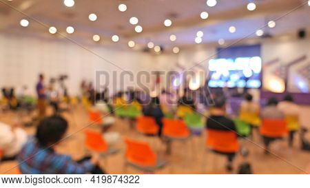 Blurred Image Of People Sit In Hall For Seminar. Arrange Social Distancing Seat For Reduce Infection