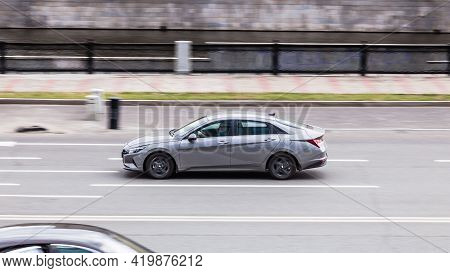 Hyundai Elantra Seventh Generation Cn7 At The City Road In Motion. Gray Car Driving Along The Presne