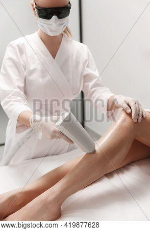 Laser Hair Removal On Legs. Beautician In Protective Glasses Remove Hair With Laser Hardware Cosmeto