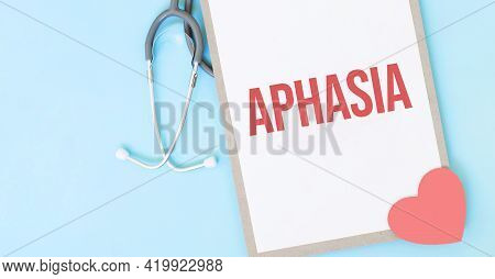 Grey Stethoscope And Paper Plate With A Sheet Of White Paper With Text Aphasia Light Blue Backround.