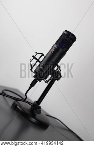 Generic Cardioid Microphone With And Shock Mount And Live Red Led In A Clean Setting.