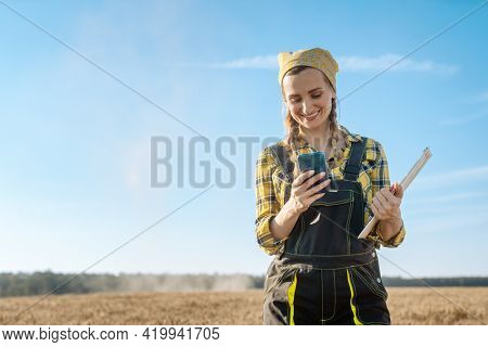 Farmer using her phone on a grain field
