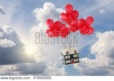Toy House With Red Balloons Floating In The Blue Sky With Sunshine And White Fluffy Clouds. Soaring 