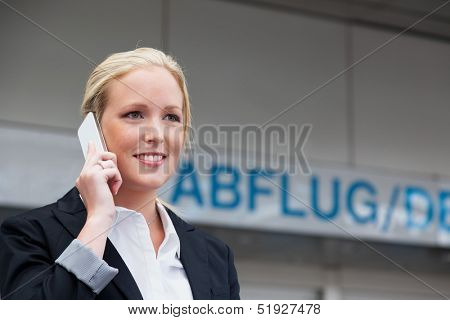 a business woman phoning with her cell phone at the airport. roaminggebÃ?Ã??Ã?Ã?Ã?ÃÂ¼rhen smartphones abroad