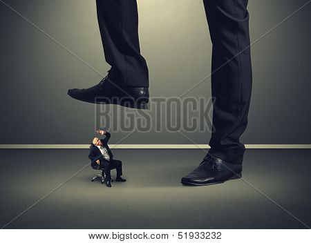 scared senior businessman under big leg his boss