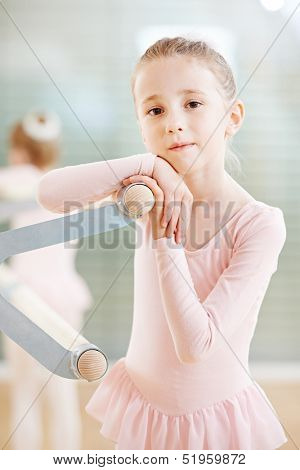 Little girl in ballet suit at training exercise in front of mirror