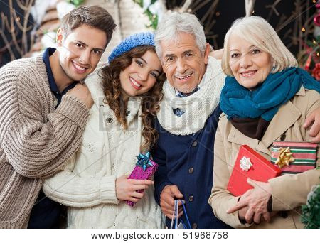Portrait of happy loving family with Christmas presents and shopping bags standing in store