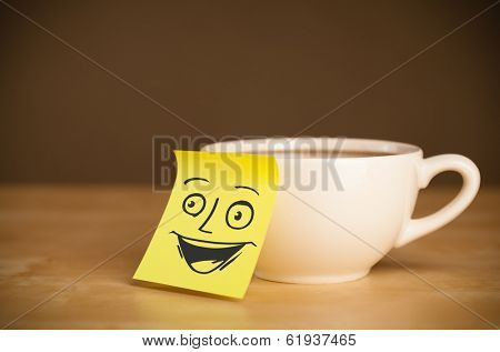 Drawn smiley face on a post-it note sticked on a mug