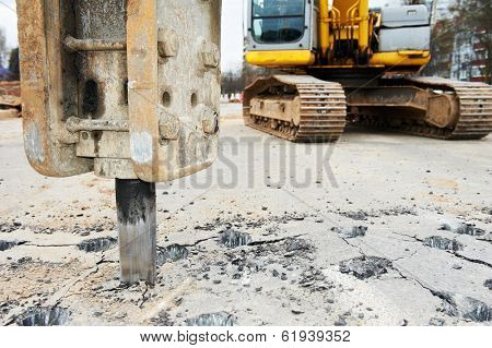 Excavator breaking street asphalt with hydrohammer drill at repairing roadwork