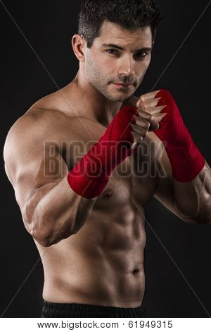 Portrait of a muscular man practicing body combat against a dark background