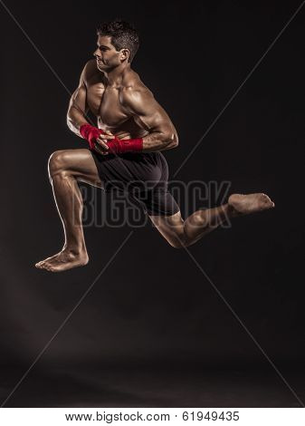 Portrait of a muscular man practicing body combat against a dark background