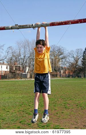 Little boy hanging on the soccer gate
