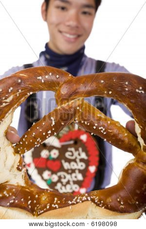 Uomo che tiene l'Oktoberfest Pretzel In Camera
