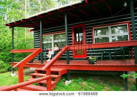 Woman sitting on a deck of log cabin