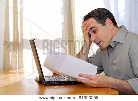 Man sitting at a desk looking at bills with horror