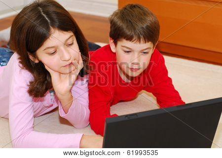 Children lying on the carpet with portable computer