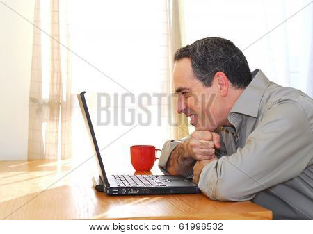 Man sitting at his desk with a laptop looking happy