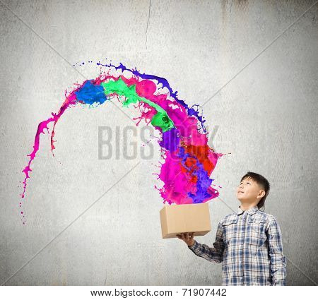 Young boy splashing colorful paint from carton box