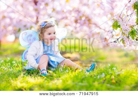 Curly Toddler Girl In Fairy Costume Playing In Fruit Garden