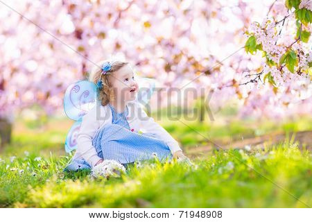 Curly Toddler Girl In Fairy Costume Playing In Fruit Garden
