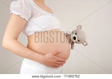 Close up on pregnant belly with toy.