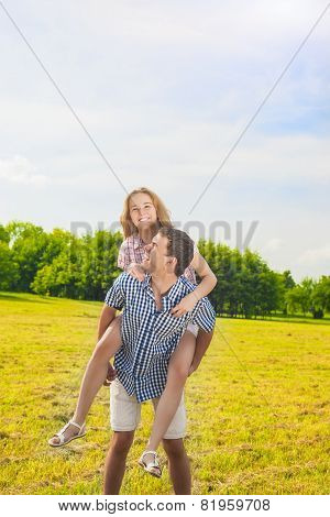 Smiling Caucasian Man Giving Woman Piggyback Ride Outdoors. Youth Lifestyle, Happiness, Love, Dating