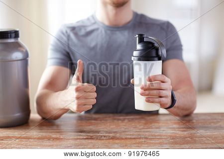sport, fitness, healthy lifestyle and people concept - close up of man in fitness bracelet with protein shake bottle showing thumbs up