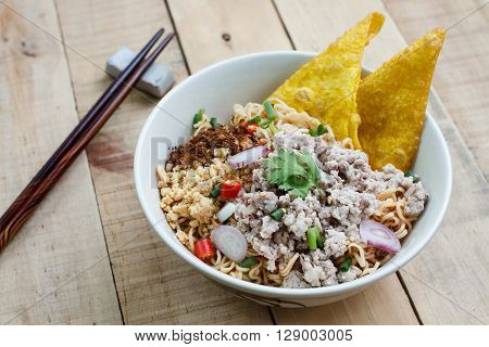 Spicy instant noodle with minced pork on wood background