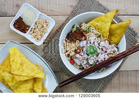 Spicy instant noodle with minced pork on wood background.Topview
