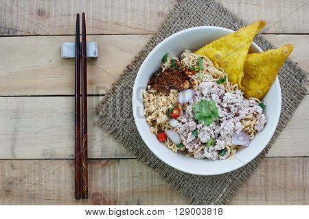 Spicy instant noodle with minced pork on wood background.Topview