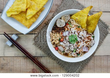 Spicy instant noodle soup with minced pork on wood background Top view